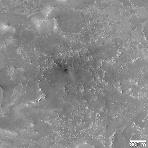 Impact site; small crater with faint dark rays among small buttes and mesas.